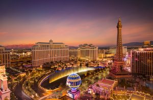 Stunning aerial view of Las Vegas skyline at sunset, featuring the Eiffel Tower and Bellagio fountains.